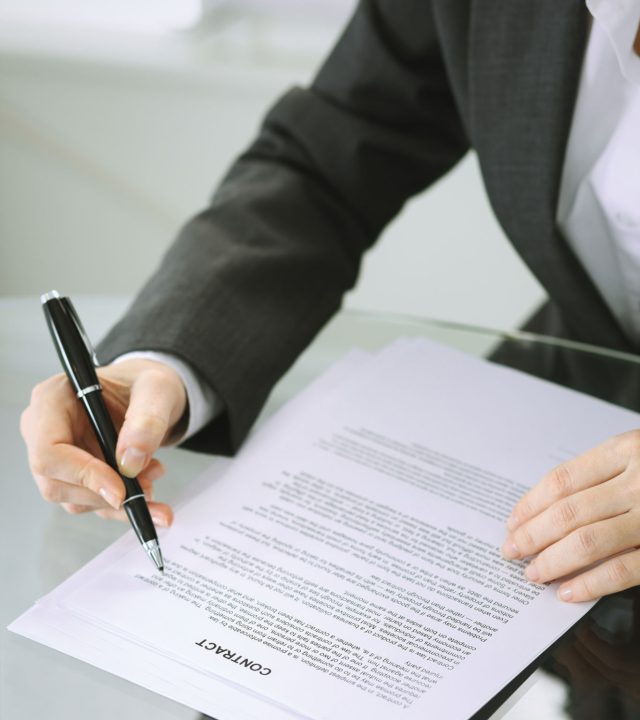 Business woman hands with pen over document of contract at glass table. Agreement signing concept.
